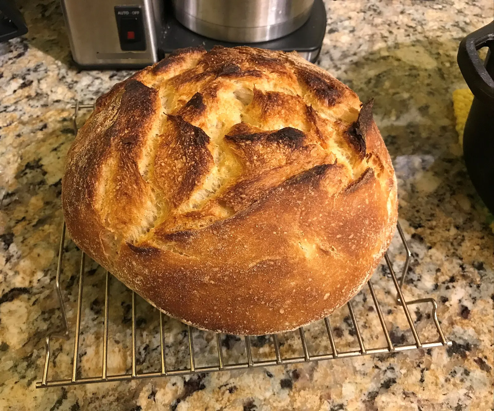 A round sourdough loaf cooling on a rack