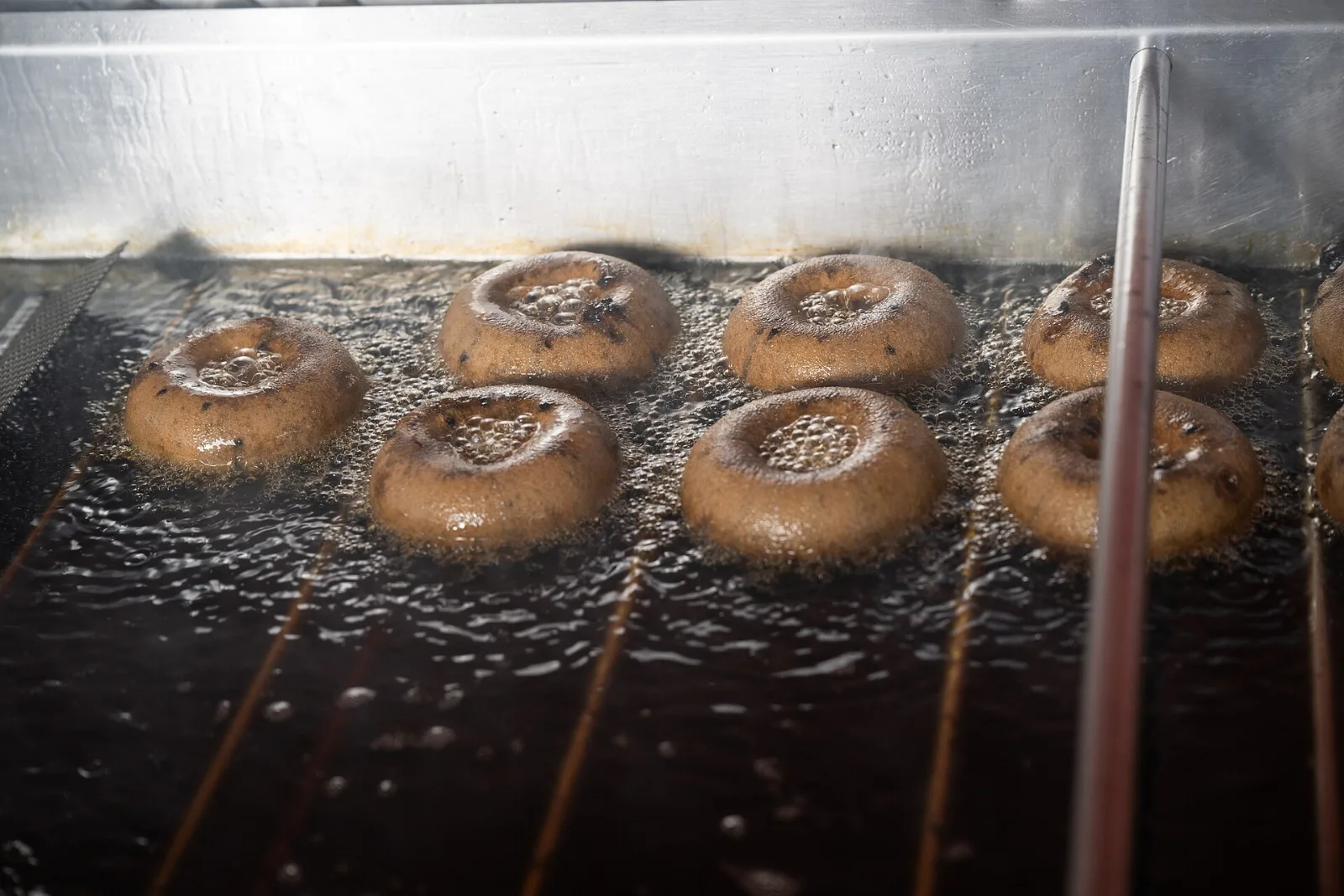 Cider donuts frying in rows in a fryer
